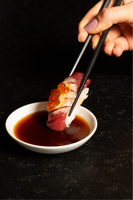 Nigiri con ikura sumergido en soya en Hi-Kov